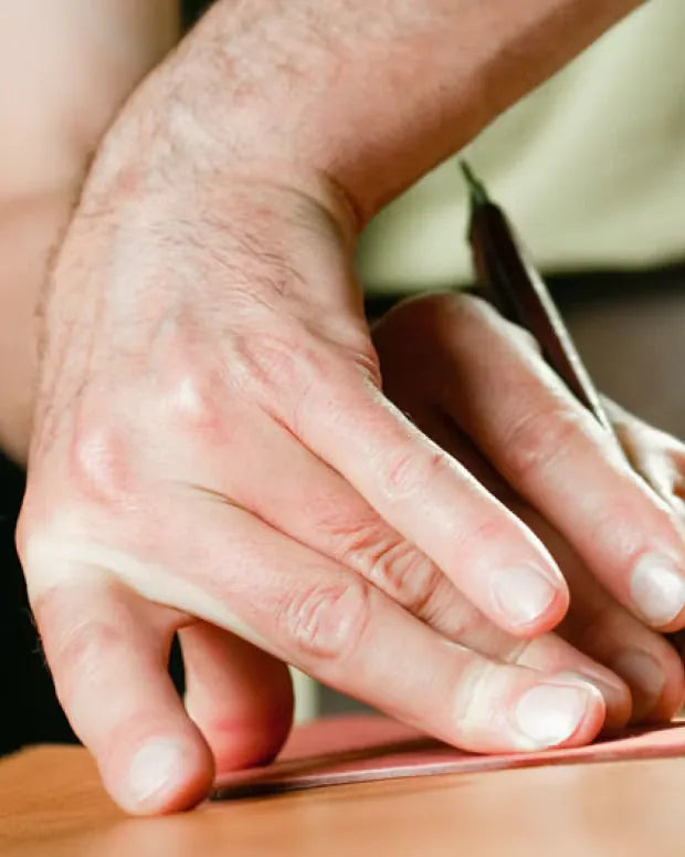 A hand cutting a piece of leather