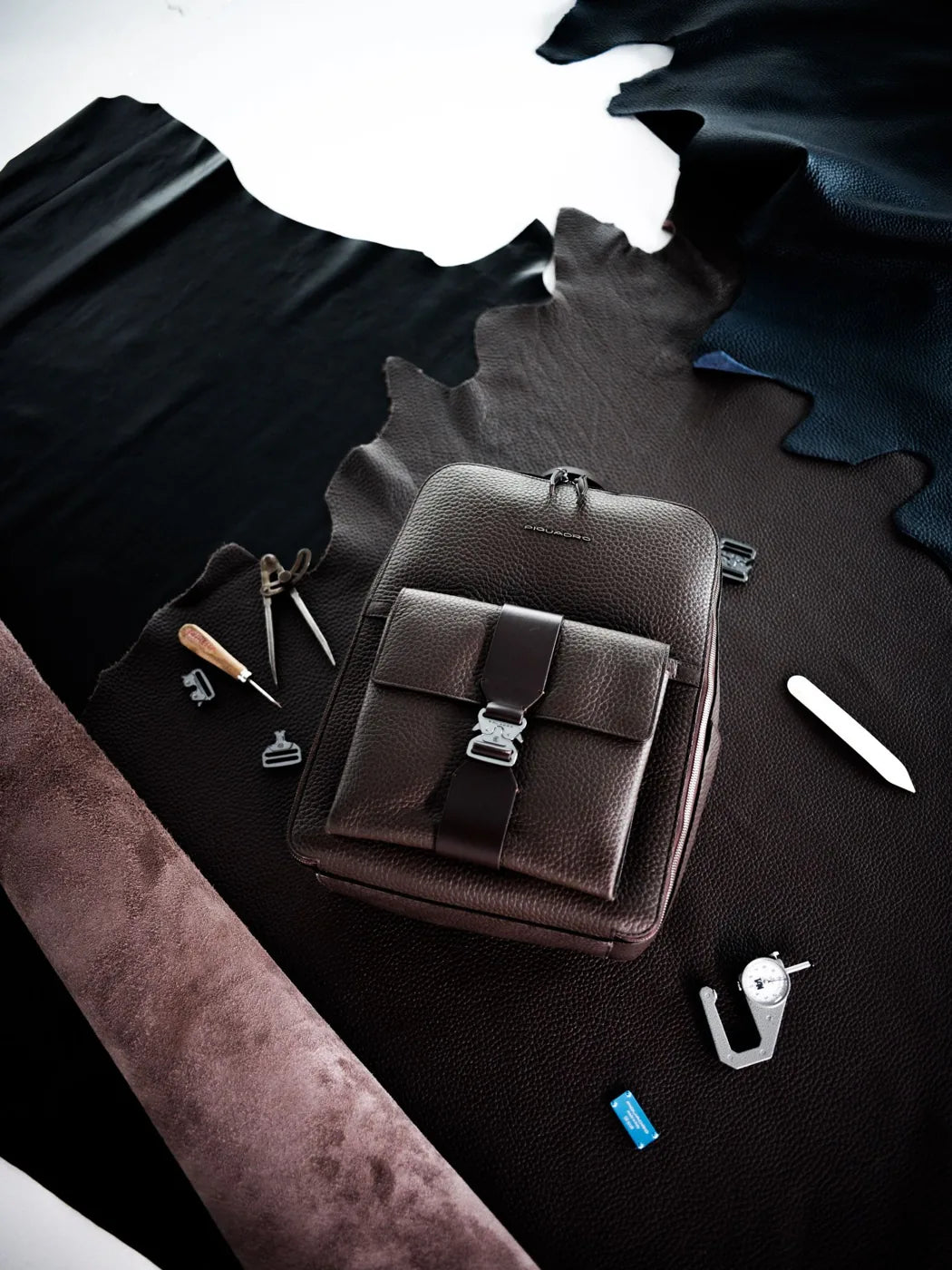 Brown leather Materia backpack among hides, dividers, an awl and a thickness gauge