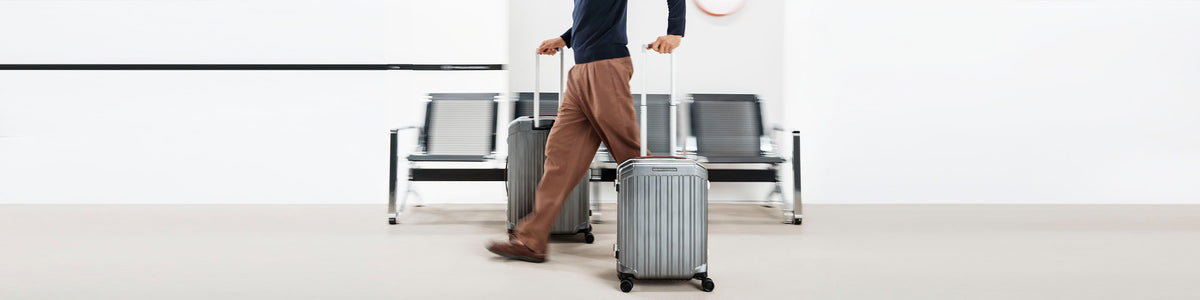 Traveller walking with Piquadro cabin trolleys in an airport